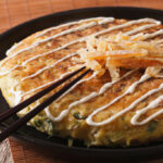 Japanese okonomiyaki on a plate close-up and chopsticks. horizontal