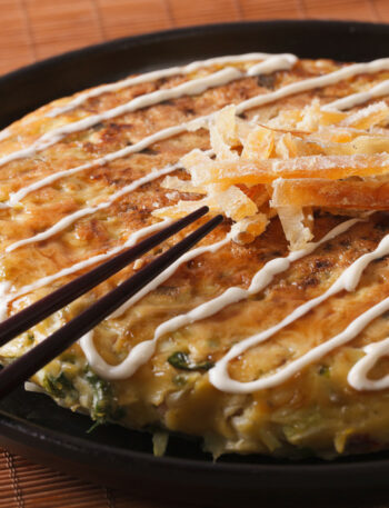 Japanese okonomiyaki on a plate close-up and chopsticks. horizontal