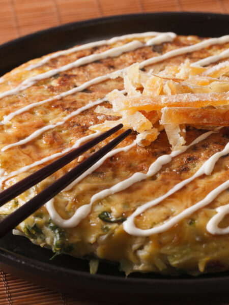 Japanese okonomiyaki on a plate close-up and chopsticks. horizontal