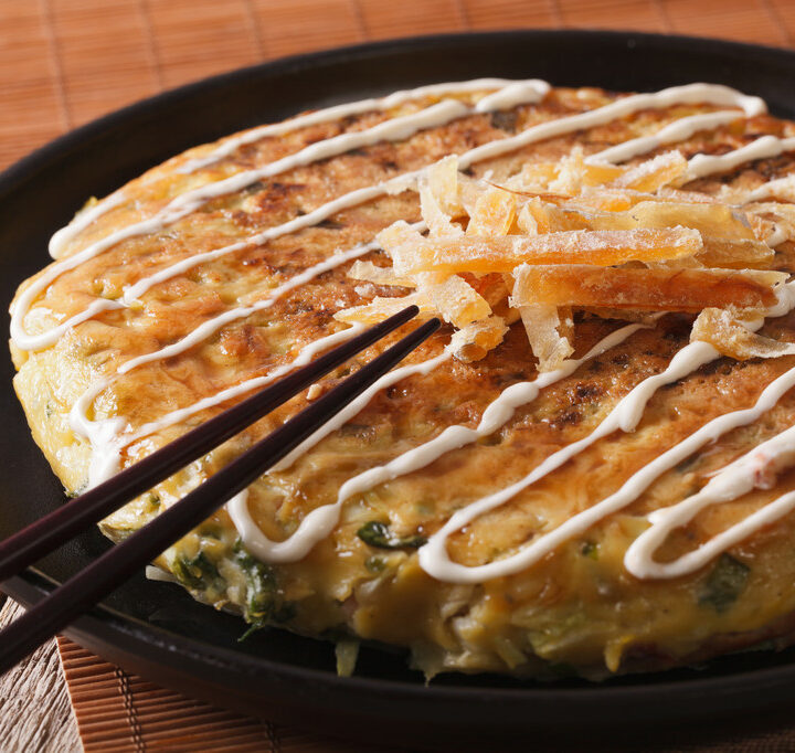 Japanese okonomiyaki on a plate close-up and chopsticks. horizontal