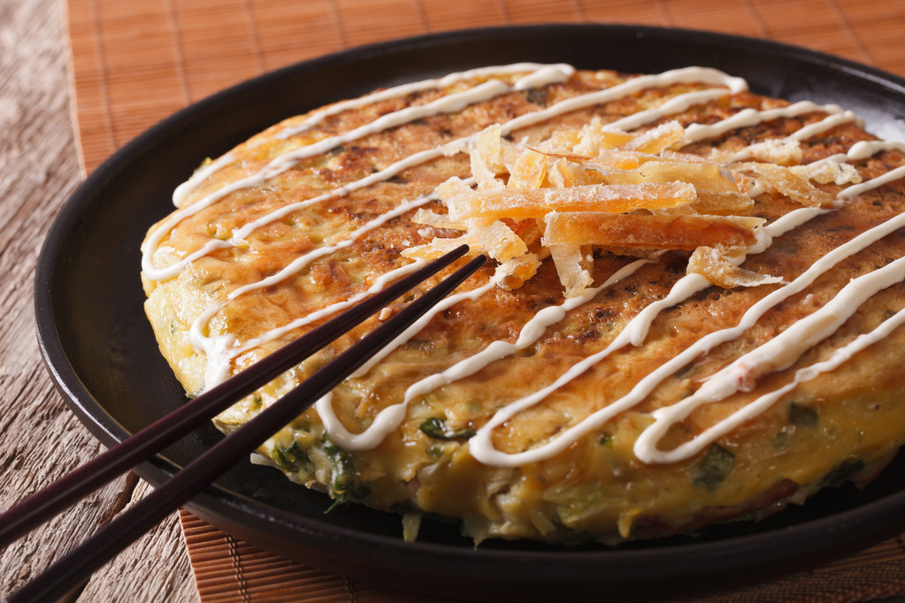 Japanese okonomiyaki on a plate close-up and chopsticks. horizontal