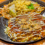 Closeup Cooking Okonomiyaki or japan pizza with hot iron frying pan.