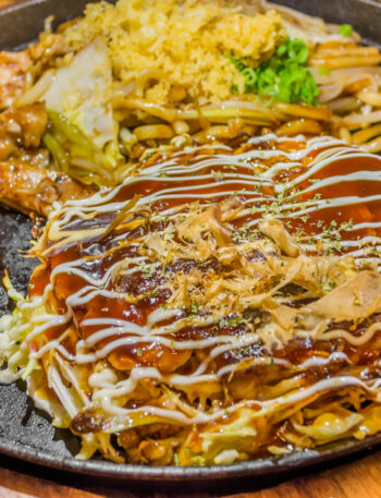 Closeup Cooking Okonomiyaki or japan pizza with hot iron frying pan.