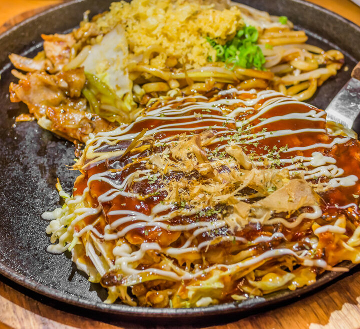 Closeup Cooking Okonomiyaki or japan pizza with hot iron frying pan.