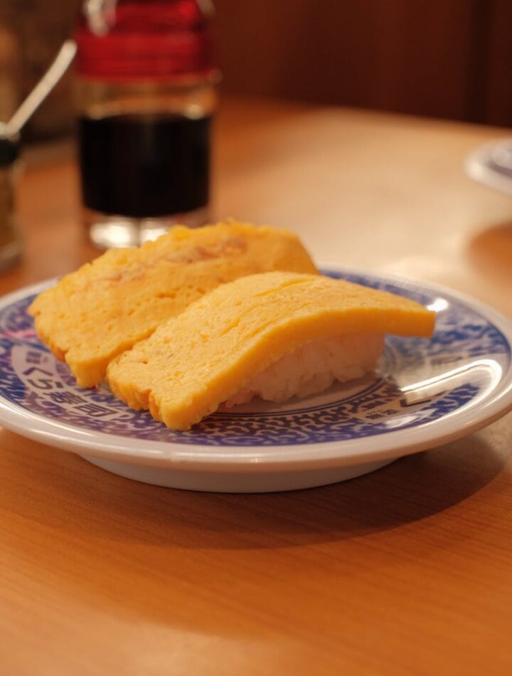 Tasty tamago sushi on a decorative blue plate, perfect for Japanese cuisine lovers.