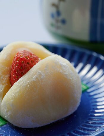 Close-up of a sweet strawberry mochi on a decorative blue plate.