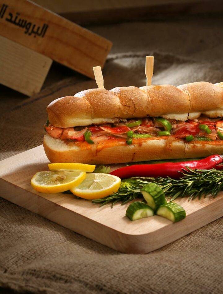 Mouth-watering sandwich with vegetables and sausage on wooden board, perfect for a delicious meal.