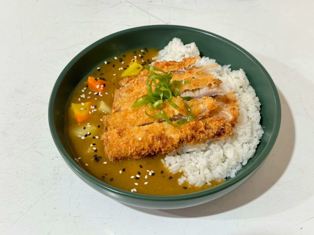 Tasty Japanese chicken katsu curry on rice garnished with sesame seeds.