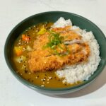 Tasty Japanese chicken katsu curry on rice garnished with sesame seeds.