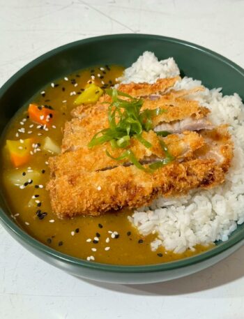 Tasty Japanese chicken katsu curry on rice garnished with sesame seeds.