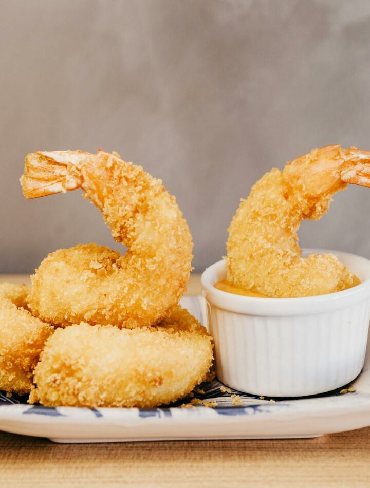 Golden crispy tempura shrimp beautifully plated on ceramic dish. tempura dipping sauce