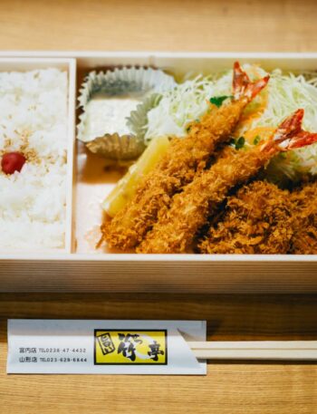 A Japanese bento box featuring rice, prawns, and salad, perfect for lunch or dinner.