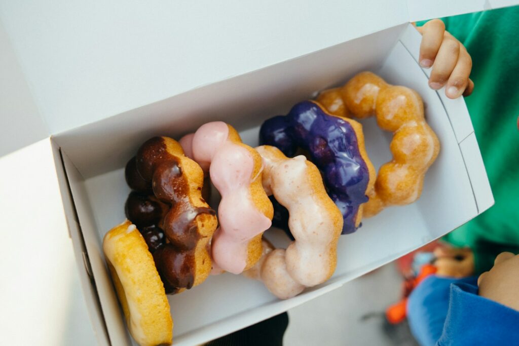 a person holding a box of mochi donuts in it