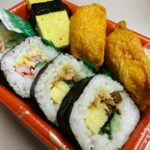 a plate of sushi with a variety of toppings, japanese bento box